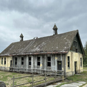 A photo of an abandon barn like building with muted colors.